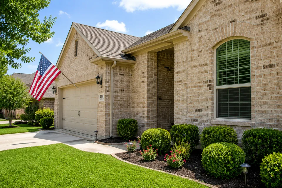 Clean brick home exterior with fresh driveway and landscaping in Garland, Texas